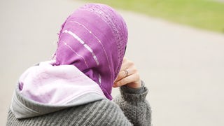 Eine junge Frau trägt ein Kopftuch und einen Kapuzenpulli