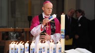 Bischof Overbeck entzündet während der Trauerfeier Kerzen für die Opfer der Loveparade