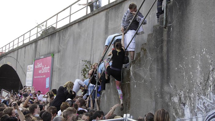 Viele Besucher der Loveparade versuchen eine schmale Treppe zu erreichen