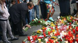 Duisburgs Bürgermeister Adolf Sauerland legt Blumen an der Trauerstelle für die Opfer der Loveparade nieder