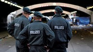 Drei Polizisten stehen vor dem Unglückstunnel der Loveparade