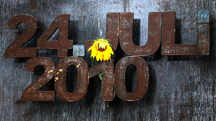 Eine Sonnenblume hängt am Denkmal an der Loveparade-Unglücksstelle