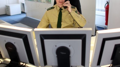 Polizist vor Monitoren mit Telefonhörer in der Hand