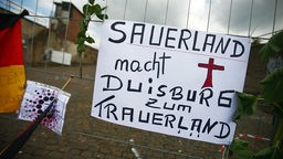 Auf einem Schild am Zugang des Loveparadegeländes wird Duisburgs Oberbürgermeister Adolf Sauerland angepangert.