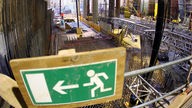 Schild mit Piktogramm für Fluchtweg an U-Bahnbaustelle