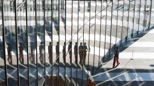 Menschen spiegeln sich in der Glasfassade des Bonner Post-Towers