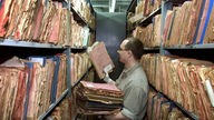 Ein Mitarbeiter des ehemaligen Stasi Archiv sortiert Karteikarten