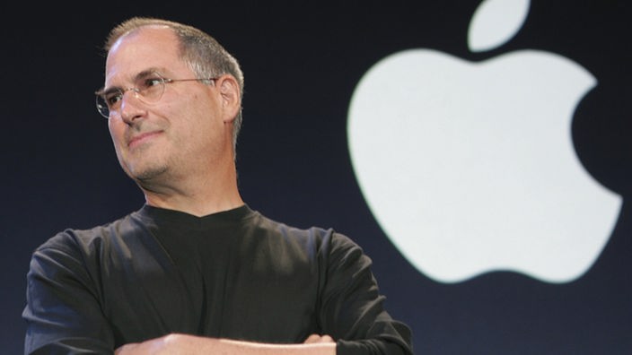 Steve Jobs im Jahr 2005 neben dem Apple-Logo