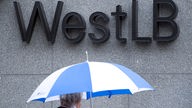 WestLB Logo an einer Wand, Frau mit Schirm