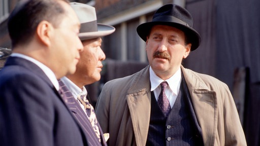 Chief Inspector Japp (Philip Jackson, r) befragt Passanten.