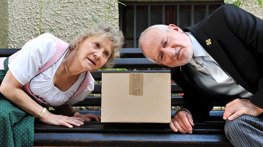 Alfons (Sepp Schauer, r.) und Hildegard (Antje Hagen, l.) horchen, ob vielleicht verdächtige Geräusche aus dem Paket kommen, das an Barbara adressiert ist.