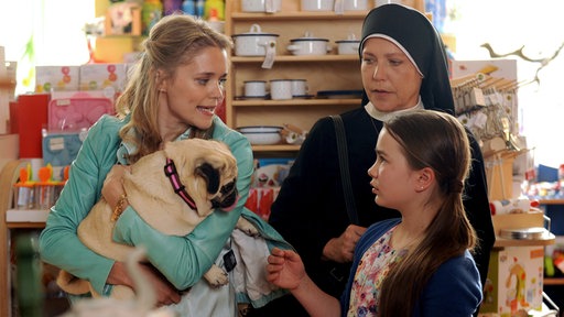 Schwester Hanna (Janina Hartwig, M.) versucht den Streit zwischen Gerlinde Kummer (Sarah Elena Timpe, l.) und Lilly Stetter (Lara Sophie Rottmann, l.) um Mops Alice zu schlichten.