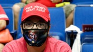 Frau mit Maske und roter Kappe mit der Aufschrift "make America great again".