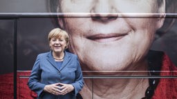 Angela Merkel steht lächelnd vor einem großen Bild ihrer selbst am Konrad Adenauer Haus
