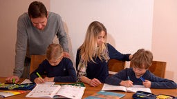 Familie, Kinder mit Lernmaterial am Tisch