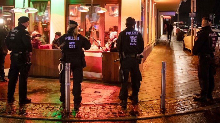 Mehrere Polizisten stehen bei einer Razzia vor einer Bar