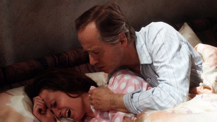 Anna (Irene Fischer) hat im Traum abermals erlebt, wie Dabelstein sich über sie geworfen hat, um mit ihr zu schlafen. Vergeblich versucht Hans (Joachim Hermann Luger) sie zu beruhigen.