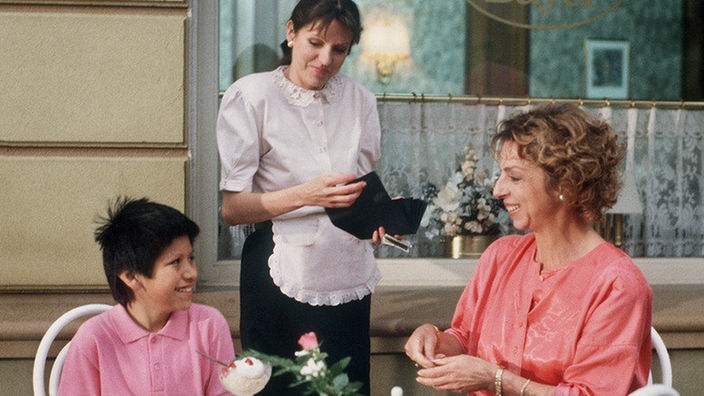Berta Griese (Ute Mora; Mitte: Anne Neunecker) spendiert ihrem Manoel (Marcel Kommissin) ein Eis.