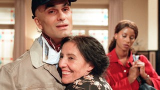 Das Schlimmste ist überstanden: Überglücklich schließt Elena (Domna Adamopoulou, Mitte) ihren Sohn Vasily (Hermes Hodolides) in die Arme. Mary (Liz Baffoe) hat ihren Mann aus der Klinik abgeholt.