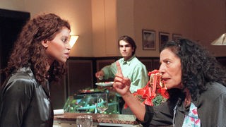 Der Streit zwischen Mary (Liz Baffoe, li) und Elena (Domna Adamopoulou) eskaliert erneut. Vasily (Hermes Hodolides) verfolgt die Diskussion.