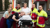 Erich, Lea, Timo, Helga und Rettungssanitäter lachen in die Kamera