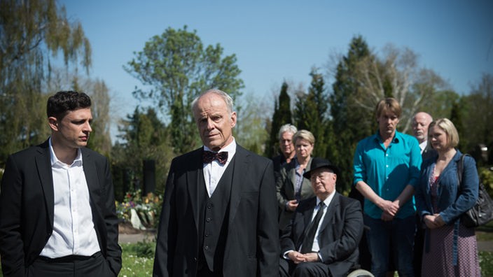 Hajo, Enzo und die Trauergemeinschaft stehen auf dem Friedhof