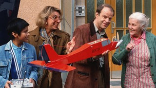 Hajo (Knut Hinz, rechts) zeigt Else (Annemarie Wendl, rechts) stolz ein selbst gebasteltes Modellflugzeug, das er gemeinsam mit Berta (Ute Mora) und Manoel (Marcel Kommissin) auf einen Jungfernflug schicken will.