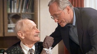 Hans (Joachim Hermann Luger, rechts) gratuliert Onkel Franz (Martin Rickelt) zu dessen 90. Geburtstag.