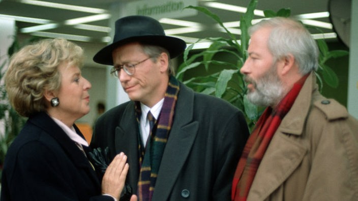 Helga (Marie-Luise Marjan) und Erich (Bill Mockridge, rechts) versuchen Hans zu überzeugen, leihweise Geld aus der Hotelkasse zu nehmen - mit Erfolg.