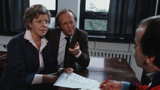 Helga (Marie-Luise Marjan) und Hans Beimer (Joachim Hermann Luger) bitten Bennys Klassenlehrer (Harry Jansen, rechts) um Verständnis für das Verhalten ihres Sohnes in der Schule.