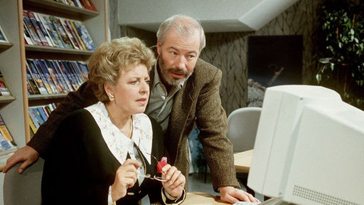 Herr Schiller (Bill Mockridge) erklärt Helga (Marie-Luise Marjan) ihren neuen Arbeitsplatz.
