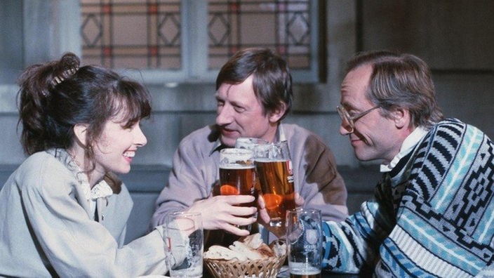 Im Biergarten des "Akropolis" trinken Vera (Ria Schindler), Franz (Raimund Gensel) und Hans (Joachim Hermann Luger, rechts) ein Bier zusammen.