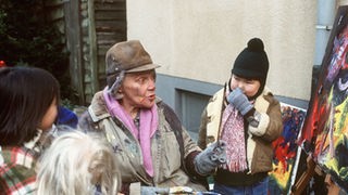 Ivo (Sascha Emelin) und Milena (Galia Emelin, links) besuchen Else (Annemarie Wendl), die sich im Hinterhof als Malerin niedergelassen hat.