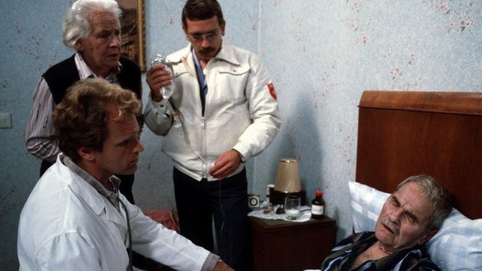 Joschi (Herbert Steinmetz, rechts) erleidet einen Herzinfarkt, weigert sich aber, ins Krankenhaus zu gehen. Philo (Johanna Bassermann) macht sich große Sorgen.