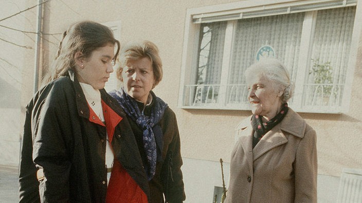 Marion (Ina Bleiweiß, links) kommt mit Helga (Marie-Luise Marjan, Mitte) nach Hause. Else Kling (Annemarie Wendl) kann sich ein paar "freundliche Kommentare" auch diesmal nicht verkneifen.