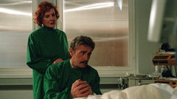 Natale (Guido Gagliardi) und Isolde (Marianne Rogée) blicken hilflos auf Enricos Krankenbett.