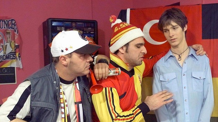 Olli (Willi Herren, links) und Murat (Erkan Gündüz) wetten mit David (Florian Köster) um den Ausgang des nächsten WM-Spiels.