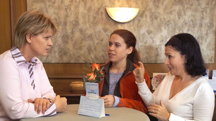 Sarah (Julia Stark, Mitte) berichtet Gabi (Andrea Spatzek, links) von der geplanten Hochzeit ihrer Eltern. Sabrina (Susanna Capurso) übersetzt mit Gebärdensprache.