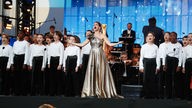 Fatma Said auf der Bühne des Concert de Paris 2024, hinter ihr ein Kinderchor