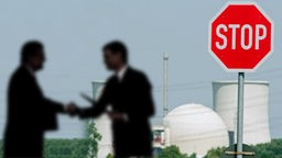Atomkraftwerk mit zwei Männern als Schatenriss, die sich die Hand geben