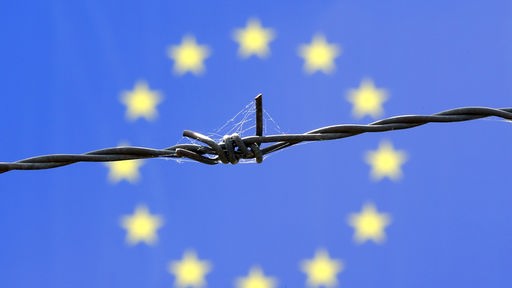 Symbolfoto EU-Grenze mit Stacheldrahtzaun vor EU-Fahne