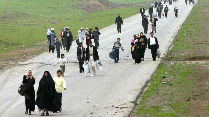 Flüchtlinge mit Handgepäck auf einer Landstraße