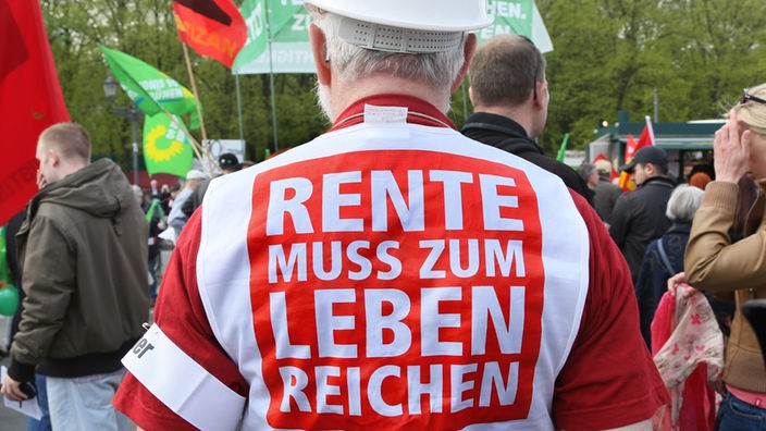 Demonstrant mit Schrift auf einer Warnweste: Rente muss zum Leben reichen