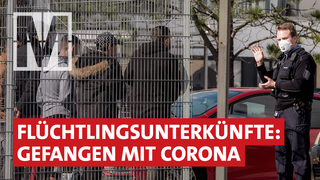 Geflüchtete stehen hinter Zaun -  Flüchtlingsunterkünfte: Gefangen mit Corona