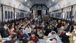 26.08.2021: Menschen, darunter afghanische Ortskräfte, sitzen auf dem Boden eines Flugzeugs der Bundeswehr