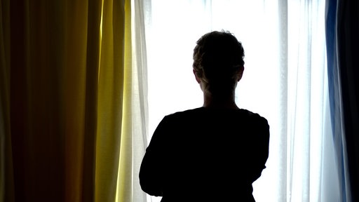 Eine junge Frau steht am Fenster in dem Zimmer eines Frauenhauses (Symbolfoto).