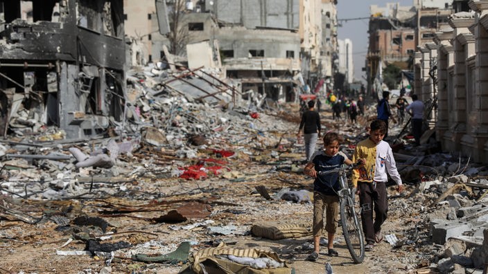 Palästinenser laufen durch eine zerstörte Straße in Gaza (24.11.2023)