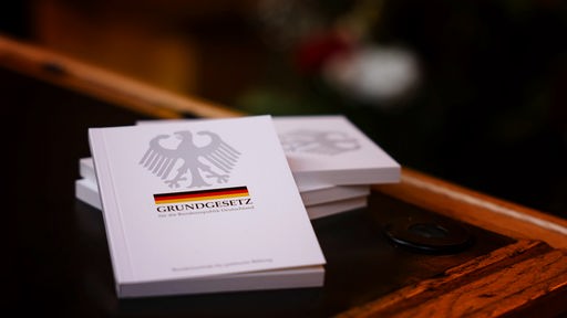 Vier Bücher mit dem Grundgesetz liegen während einer Einbürgerungsfeier auf einem Tisch im Ratssaal des Kieler Rathauses.