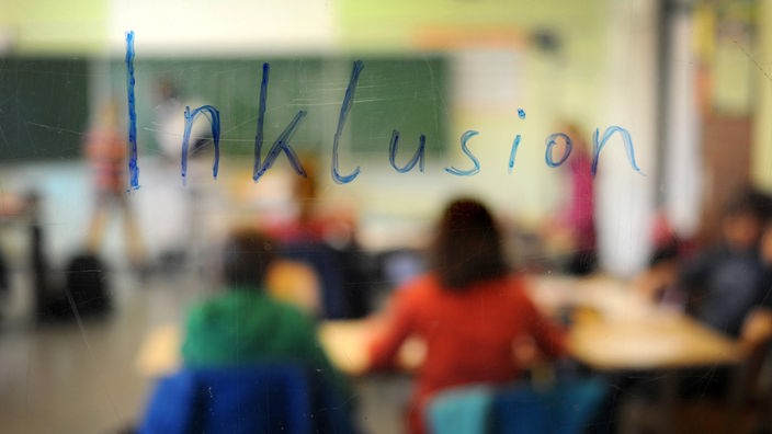 Symbolbild: Schriftzug "Inklusion" vor dem Motiv eines Klassenzimmers