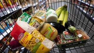 Verschiedene Lebensmittel liegen in einem Supermarkt in einem Einkaufswagen.